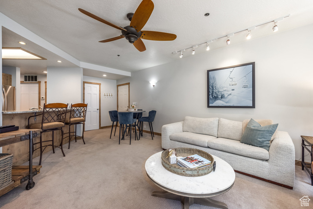 Living area featuring light carpet, ceiling fan, recessed lighting, and baseboards