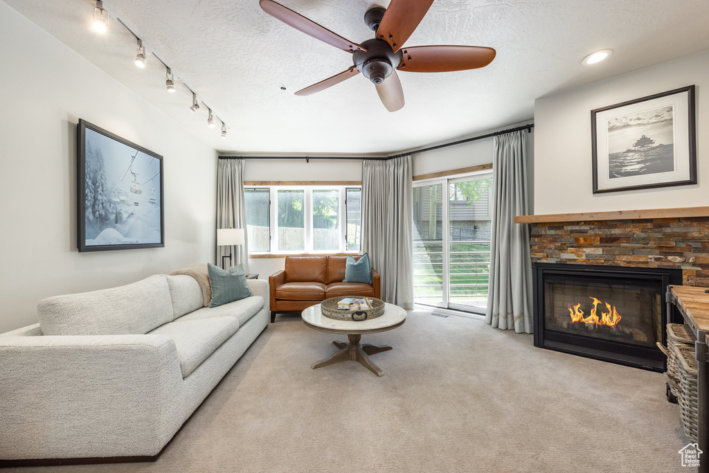 Carpeted living room with rail lighting, ceiling fan, a textured ceiling, a fireplace, and recessed lighting