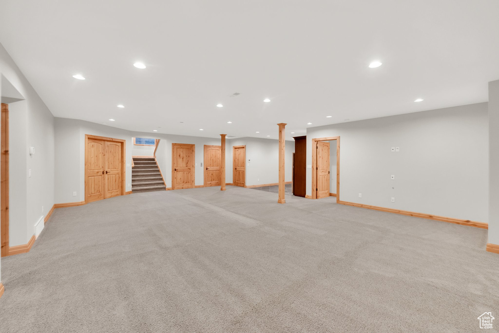 Finished below grade area with baseboards, stairway, recessed lighting, and light carpet