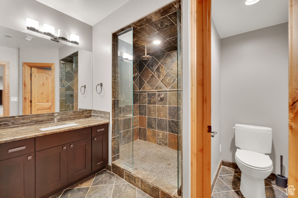 Full bathroom featuring vanity, a shower stall, toilet, and baseboards