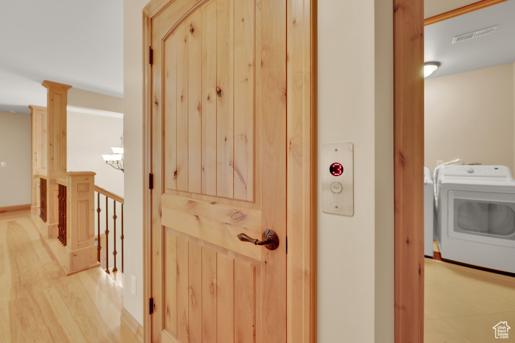 Hall with washing machine and dryer and light wood-style flooring