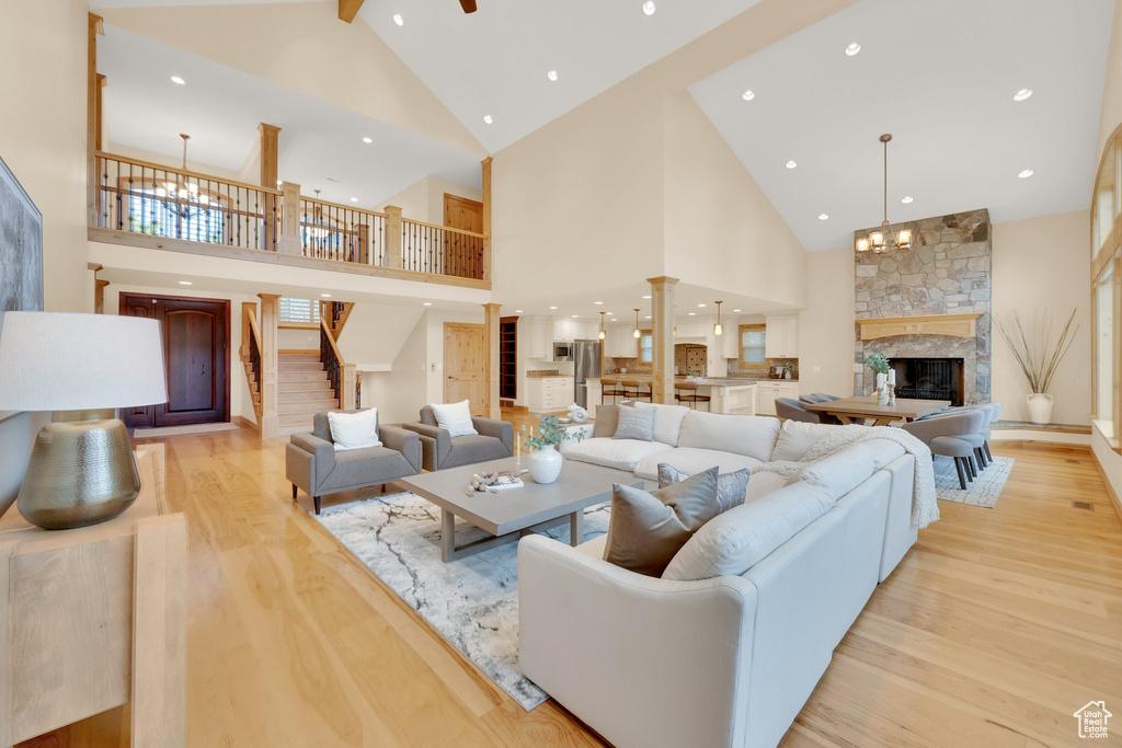 Living area featuring high vaulted ceiling, light wood finished floors, a chandelier, a fireplace, and recessed lighting