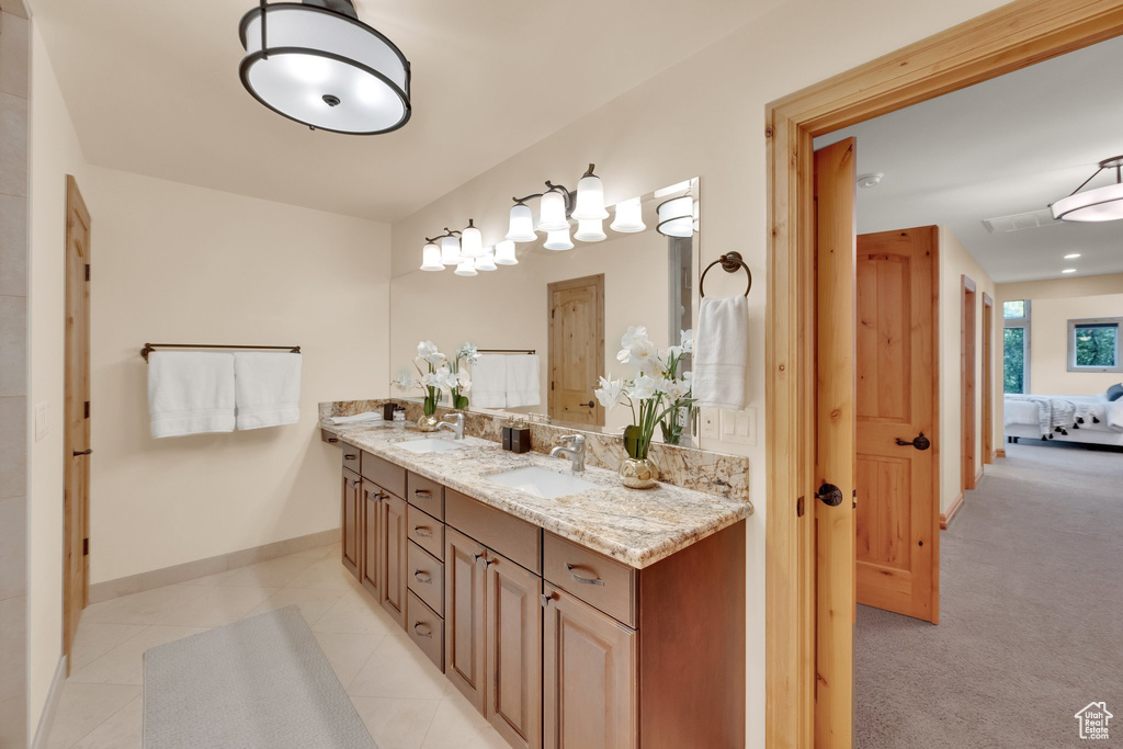 Full bathroom with double vanity, connected bathroom, baseboards, and tile patterned flooring