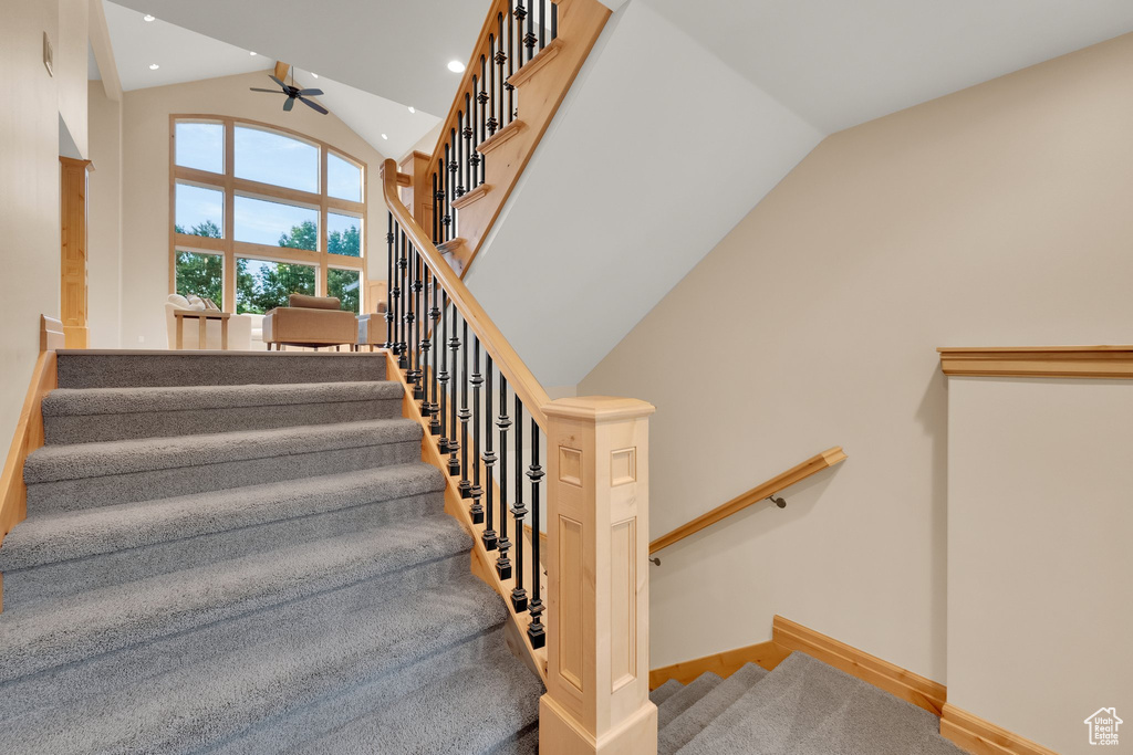 Stairs with high vaulted ceiling, a ceiling fan, baseboards, and recessed lighting
