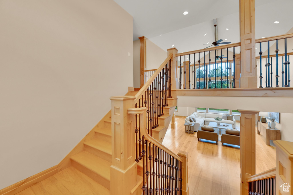 Stairs featuring a ceiling fan, wood finished floors, a towering ceiling, and recessed lighting