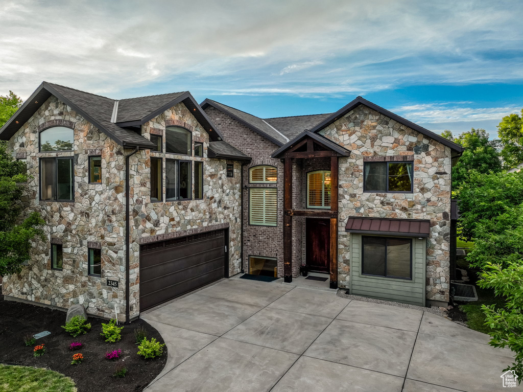 French provincial home featuring stone siding, a garage, concrete driveway, and a shingled roof