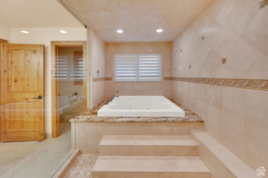 Bathroom with a tub with jets, tile walls, recessed lighting, and tile patterned floors