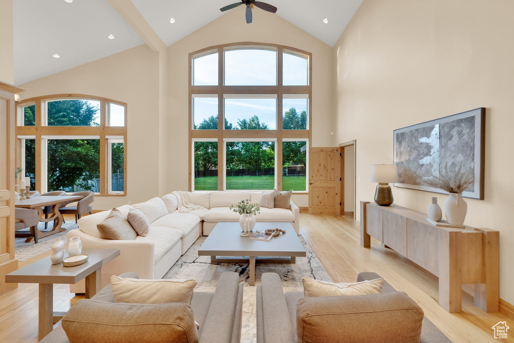 Living area featuring high vaulted ceiling, light wood-type flooring, ceiling fan, and healthy amount of natural light