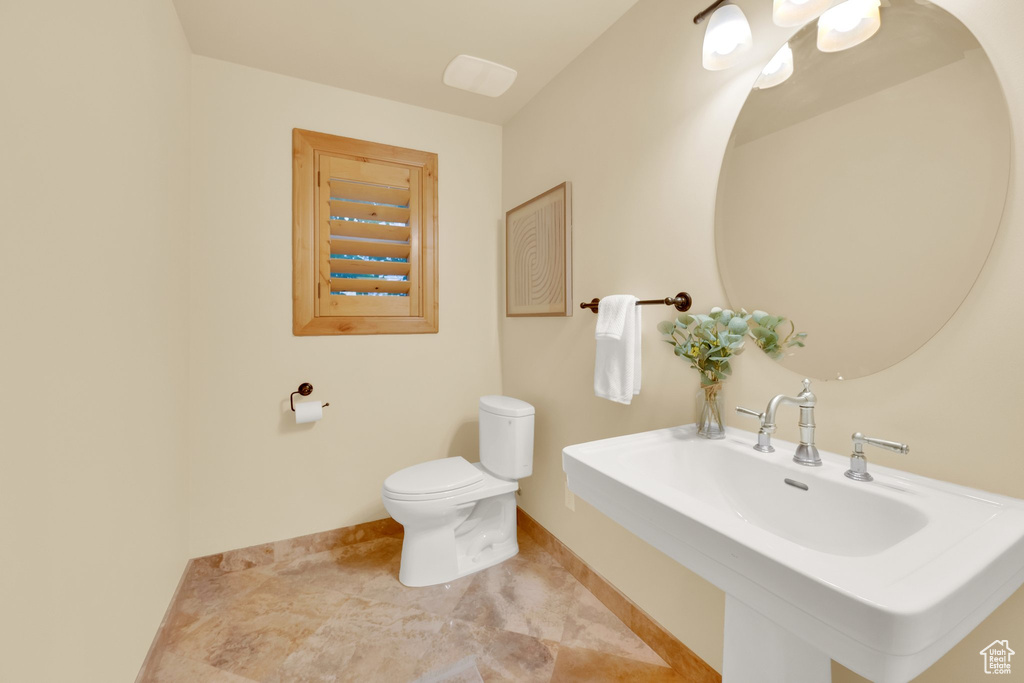 Bathroom featuring toilet, a sink, and baseboards