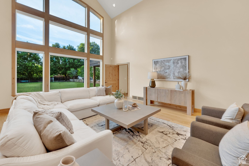 Living area with wood finished floors, high vaulted ceiling, and baseboards