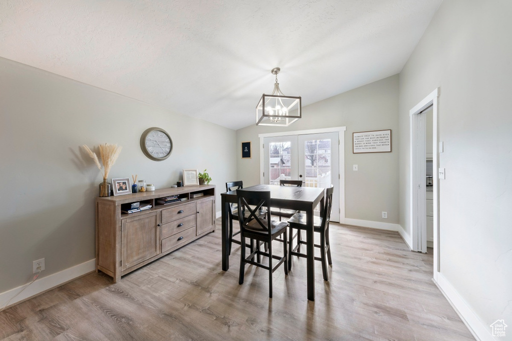 Dining space with vaulted ceiling, a chandelier, light wood-style flooring, and baseboards
