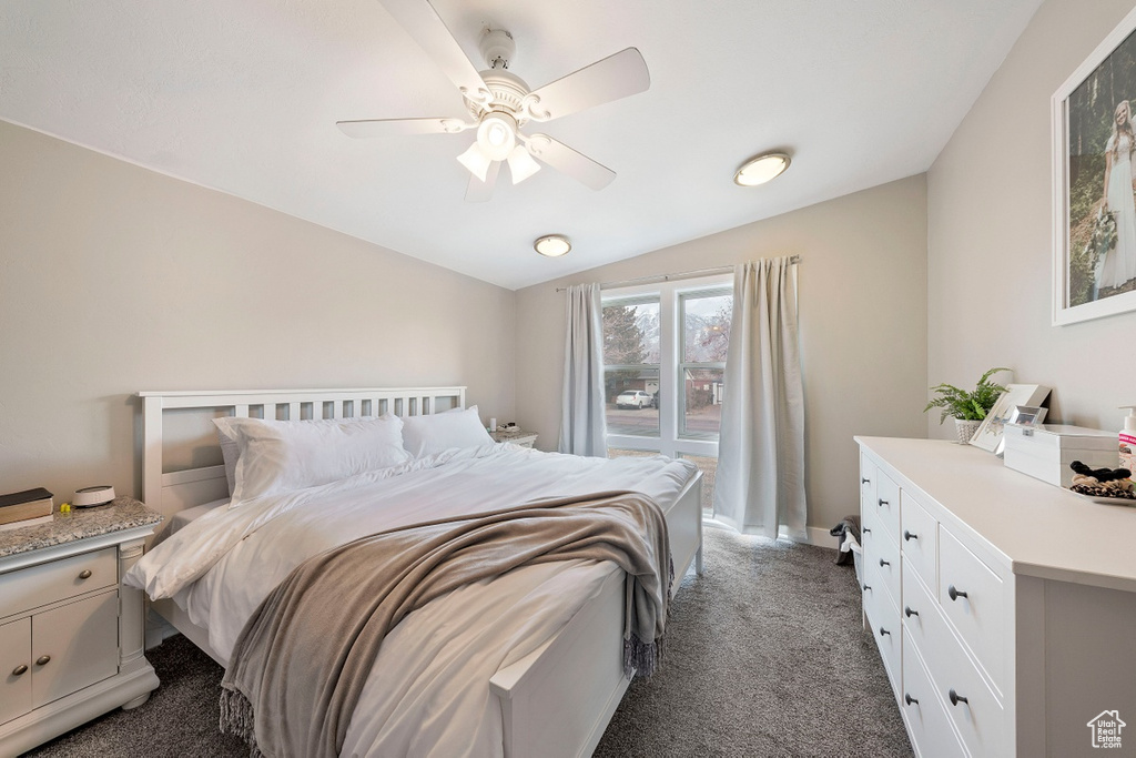 Bedroom featuring dark colored carpet, lofted ceiling, a ceiling fan, and baseboards