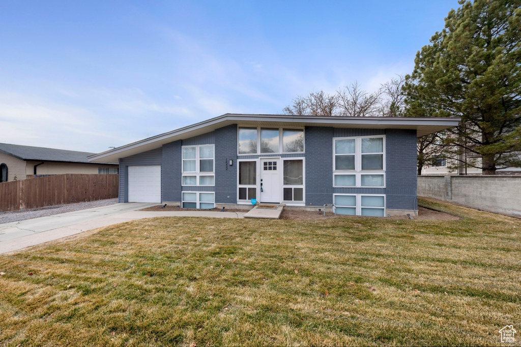 Mid-century home with concrete driveway, brick siding, and an attached garage
