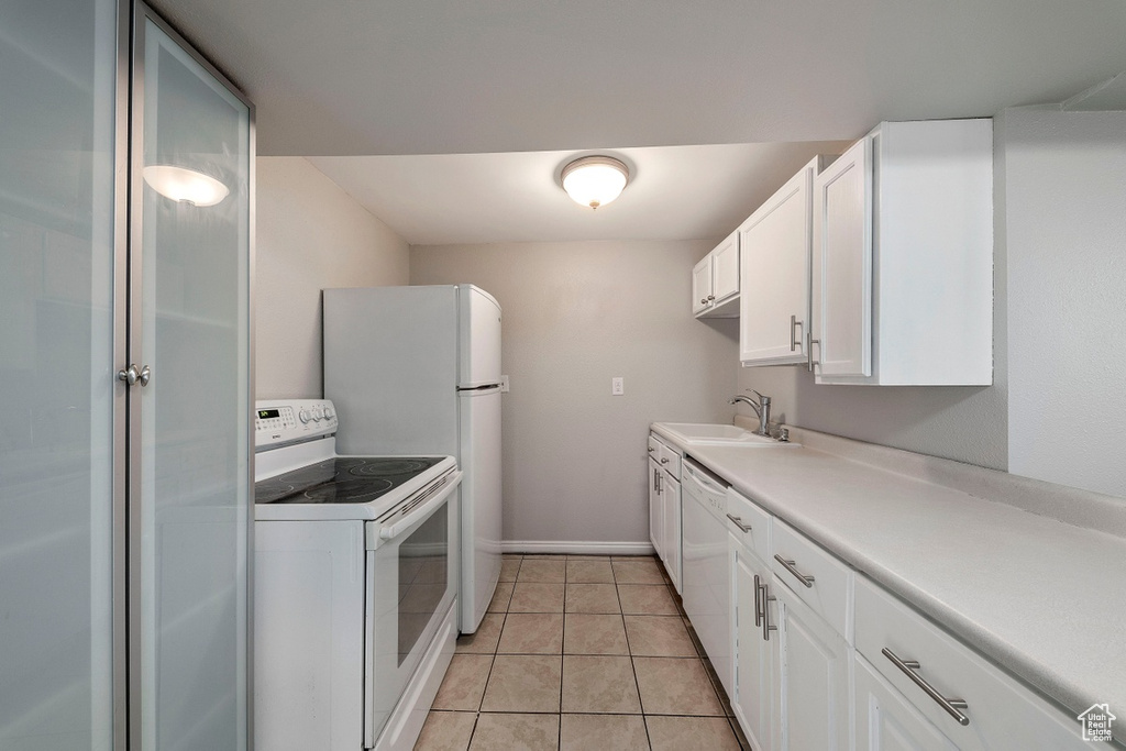 Kitchen featuring white appliances, a sink, white cabinets, light countertops, and light tile patterned floors