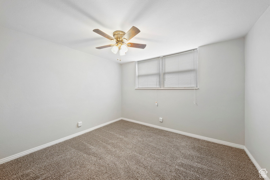 Carpeted empty room featuring ceiling fan and baseboards