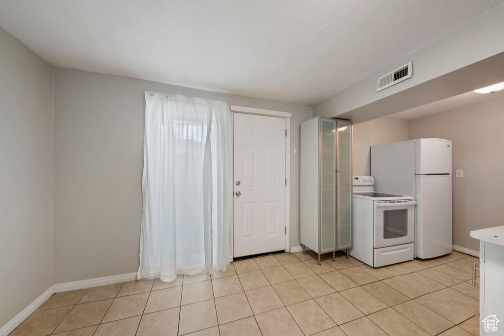 Kitchen with white appliances, baseboards, light tile patterned flooring, and light countertops