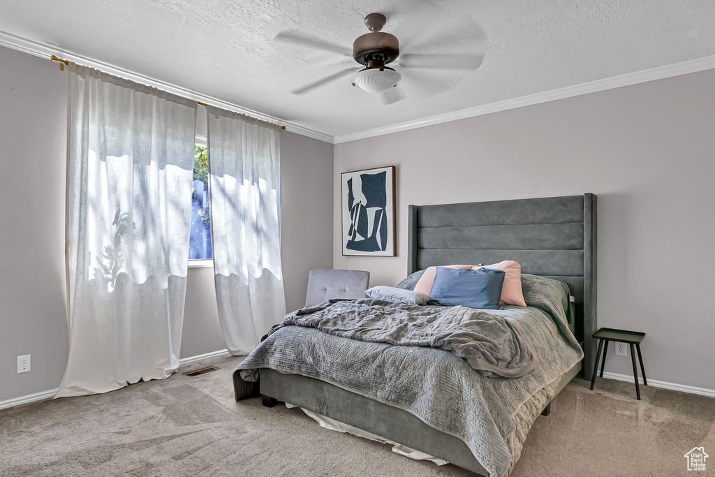 Carpeted bedroom featuring ornamental molding, baseboards, a ceiling fan, and a textured ceiling