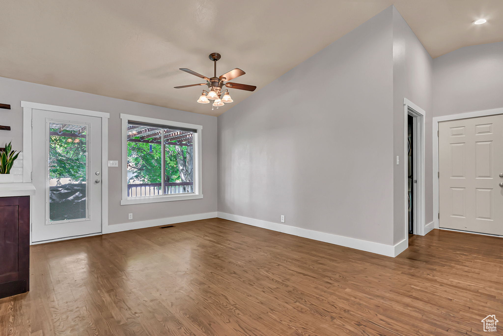 Unfurnished living room featuring a ceiling fan, baseboards, wood finished floors, and lofted ceiling