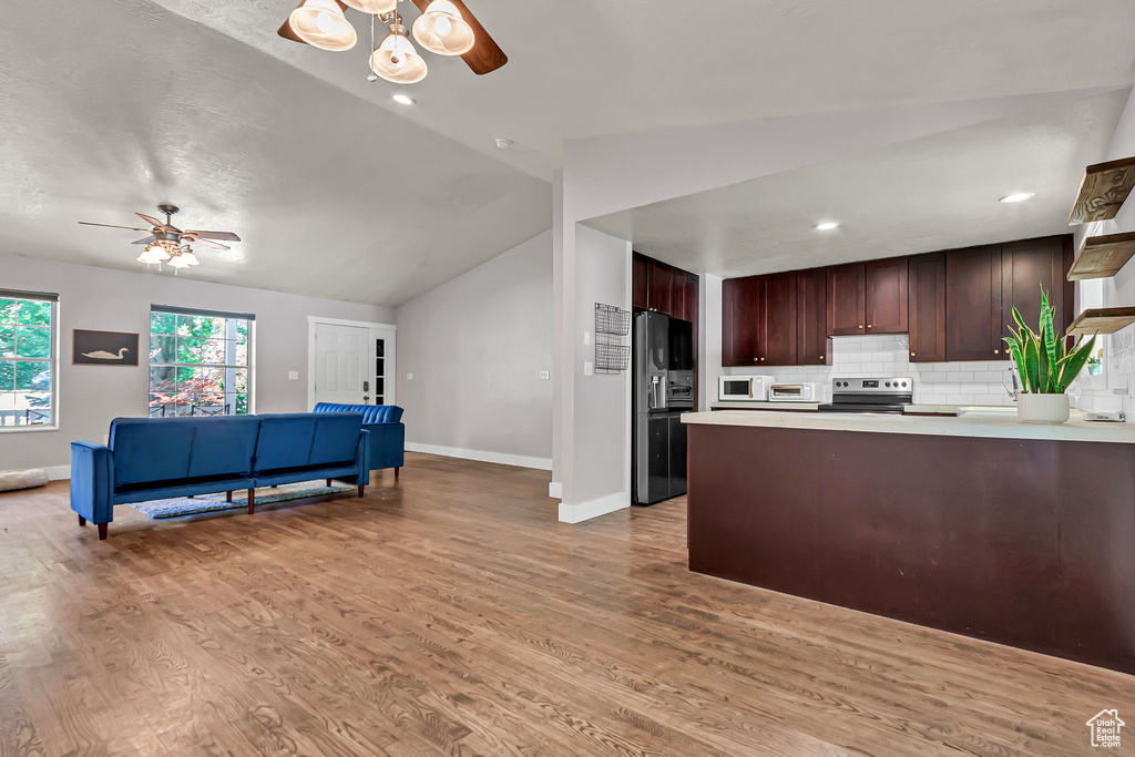 Kitchen with fridge with ice dispenser, ceiling fan, stainless steel range with electric cooktop, baseboards, and lofted ceiling