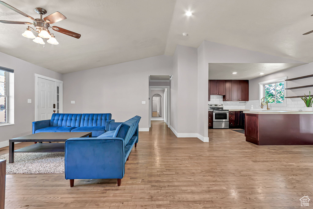 Living area featuring lofted ceiling, ceiling fan, light wood-type flooring, baseboards, and recessed lighting