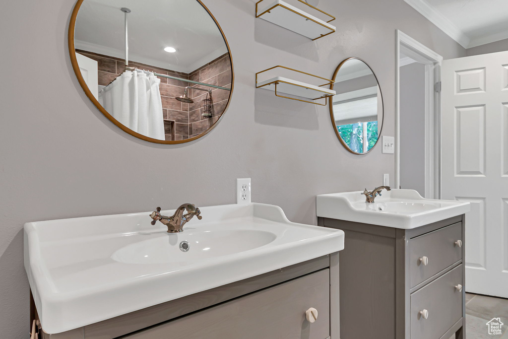Bathroom with ornamental molding, two vanities, and a shower with shower curtain