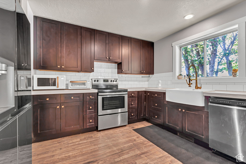 Kitchen with stainless steel appliances, a sink, backsplash, light countertops, and recessed lighting