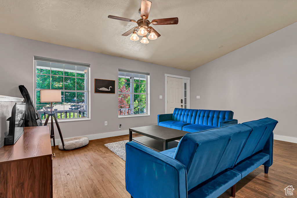 Living area featuring baseboards, a ceiling fan, hardwood / wood-style flooring, and lofted ceiling