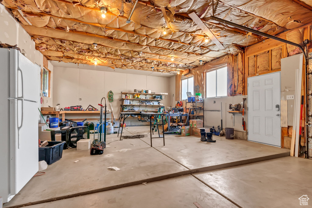Basement with freestanding refrigerator and a workshop area