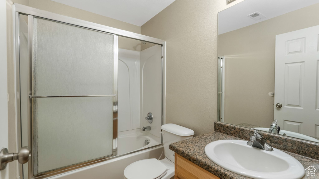 Full bathroom featuring vanity, toilet, and shower / bath combination with glass door