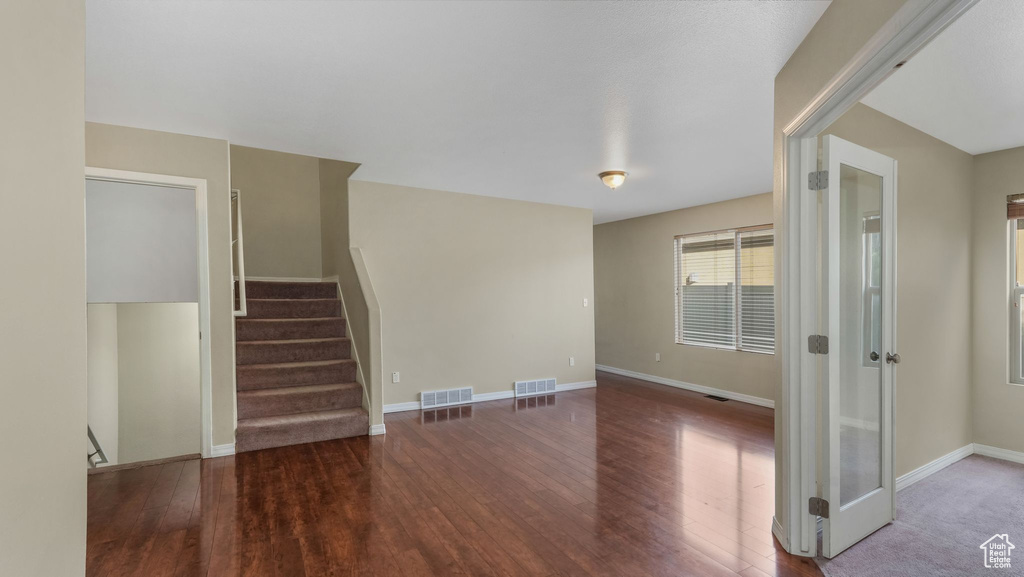 Unfurnished living room with wood finished floors, baseboards, and stairway