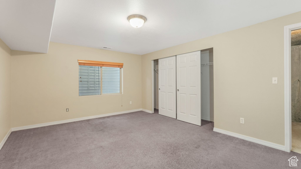 Unfurnished bedroom with carpet floors, baseboards, and a closet