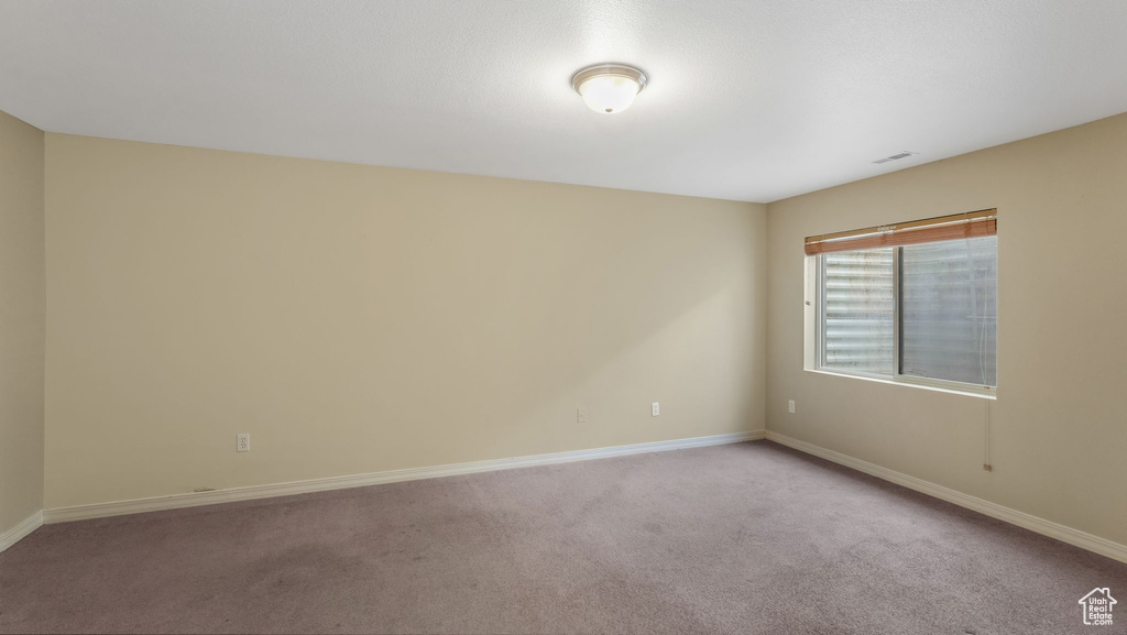 Carpeted spare room featuring baseboards
