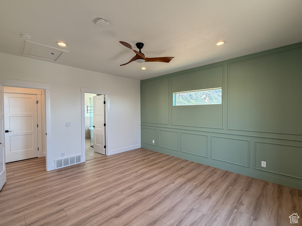 Unfurnished room with light wood finished floors, ceiling fan, recessed lighting, attic access, and a decorative wall