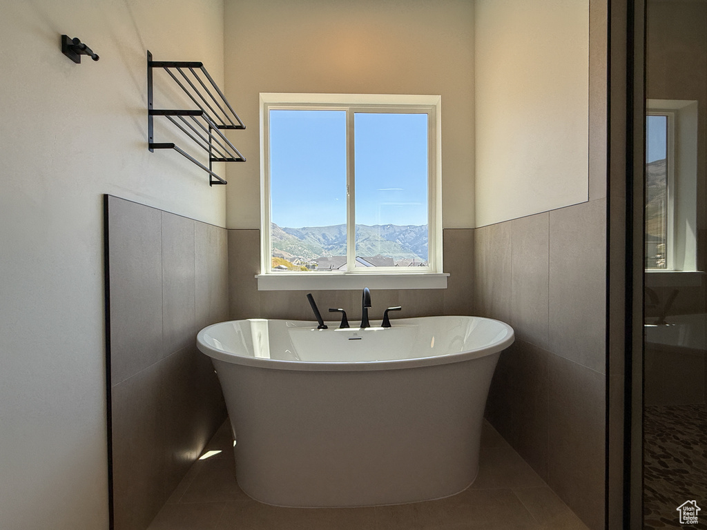 Bathroom featuring a soaking tub, wainscoting, and tile patterned floors