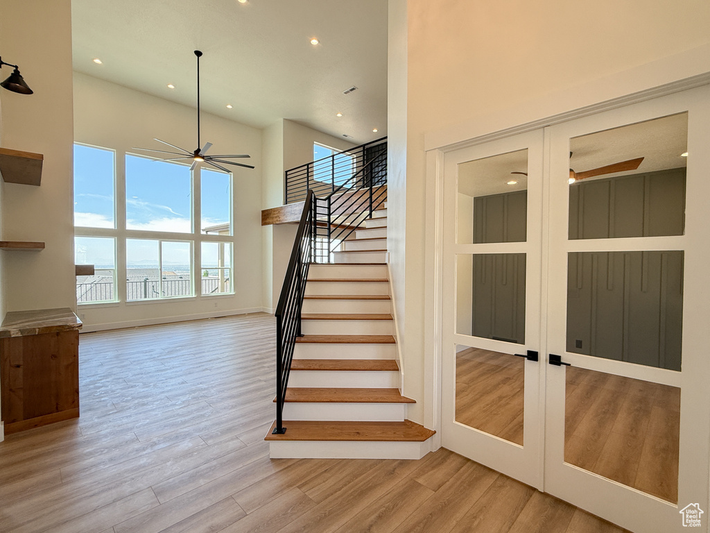 Stairway with a ceiling fan, recessed lighting, wood finished floors, baseboards, and a towering ceiling