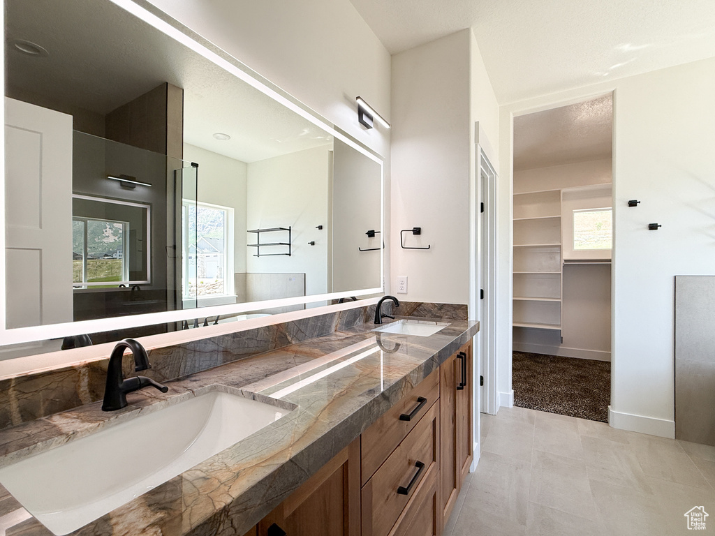 Full bath featuring double vanity, plenty of natural light, and baseboards