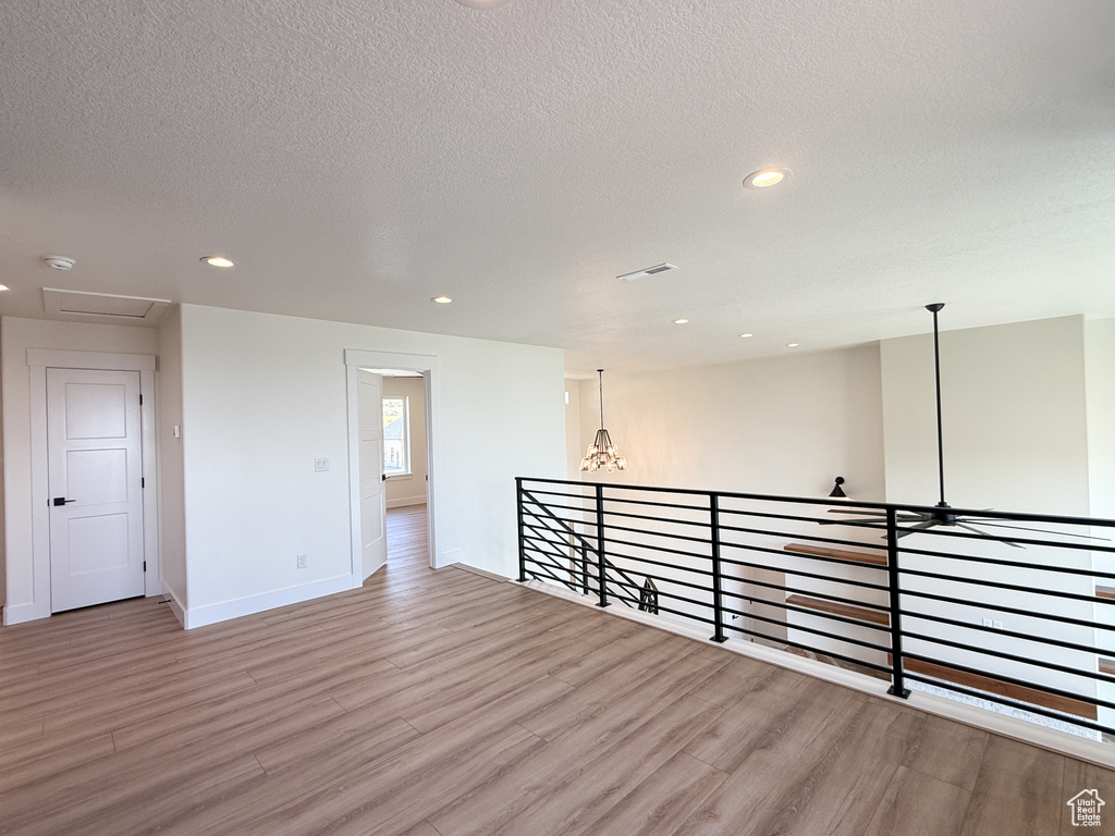 Empty room with light wood-type flooring, baseboards, recessed lighting, and a textured ceiling