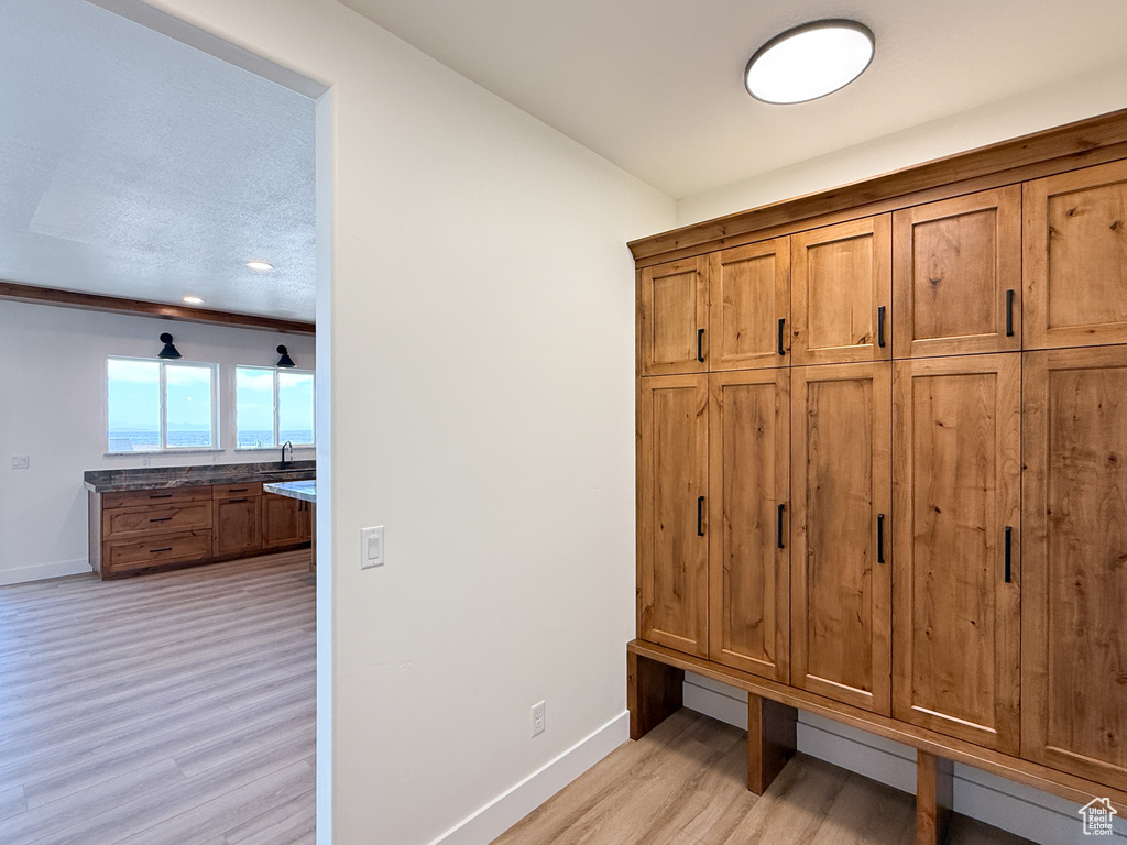 Mudroom featuring baseboards, light wood-style floors, and a sink