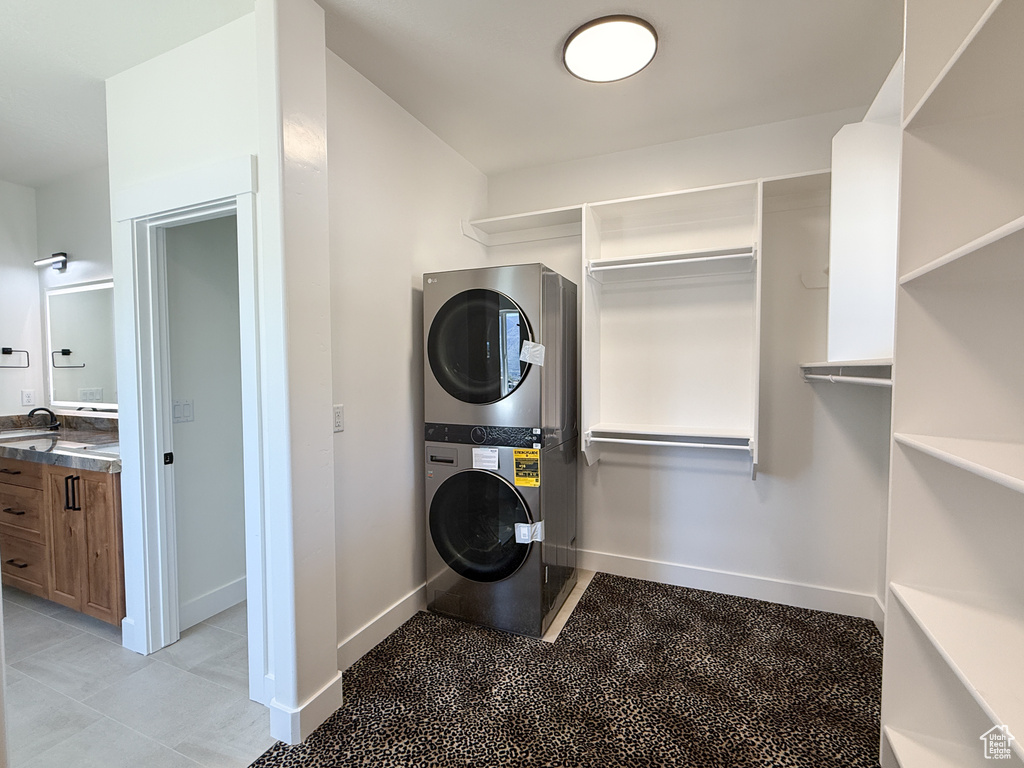 Laundry area featuring stacked washer and clothes dryer and baseboards