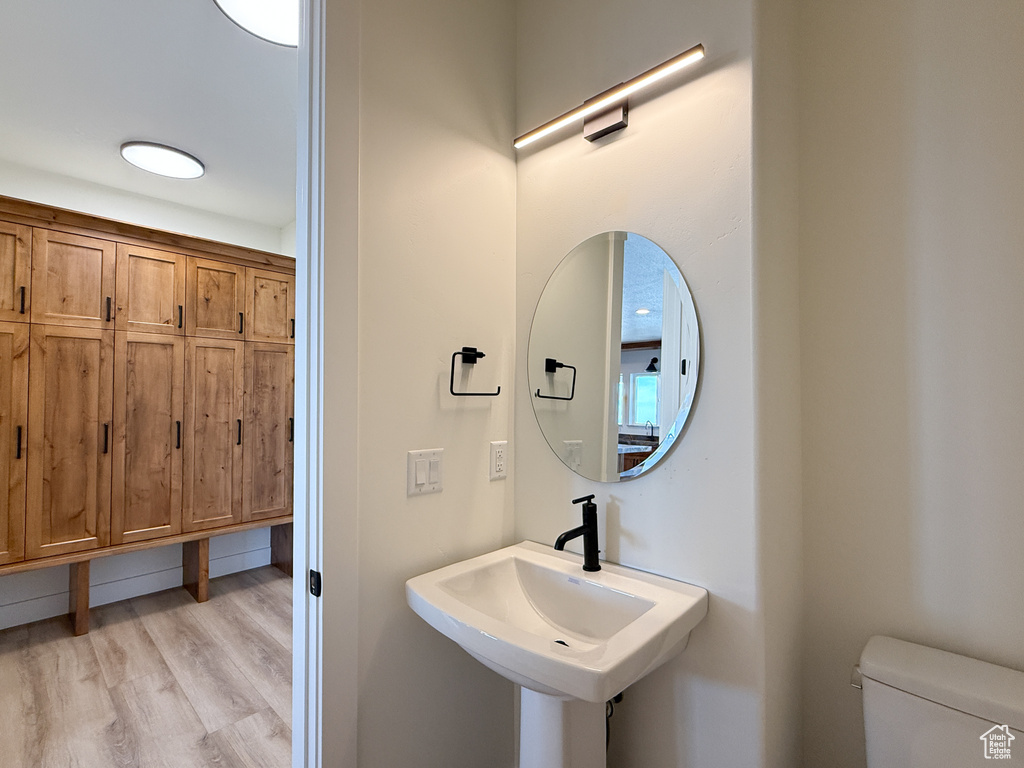 Half bath featuring wood finished floors, toilet, and a sink
