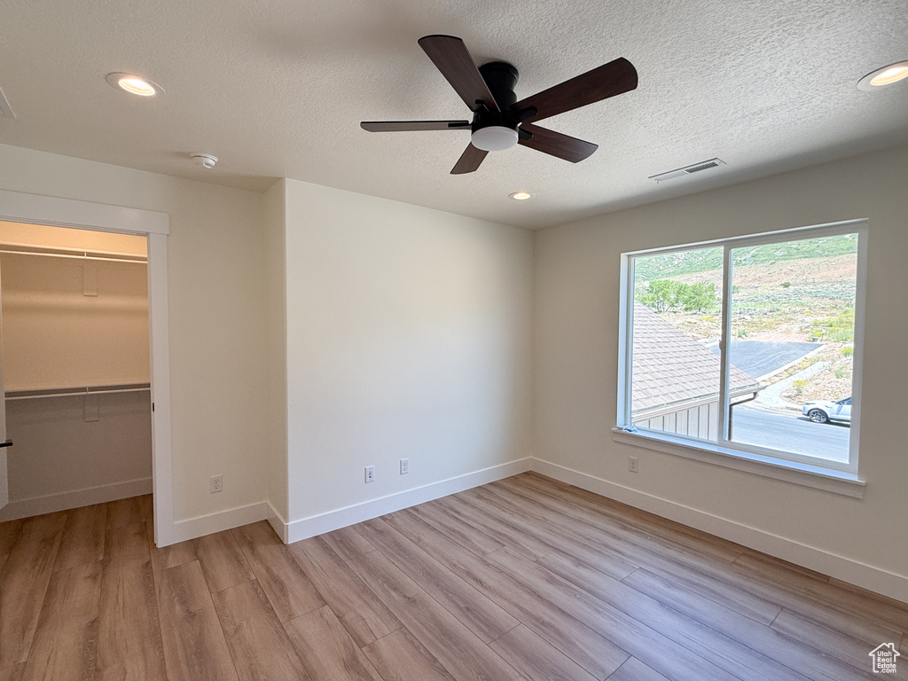 Unfurnished bedroom with light wood-type flooring, a walk in closet, baseboards, recessed lighting, and a ceiling fan