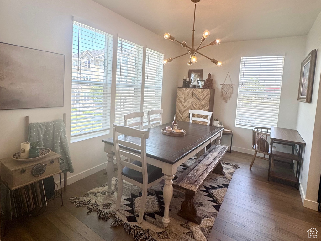 Dining space with a chandelier, dark wood-style flooring, and baseboards