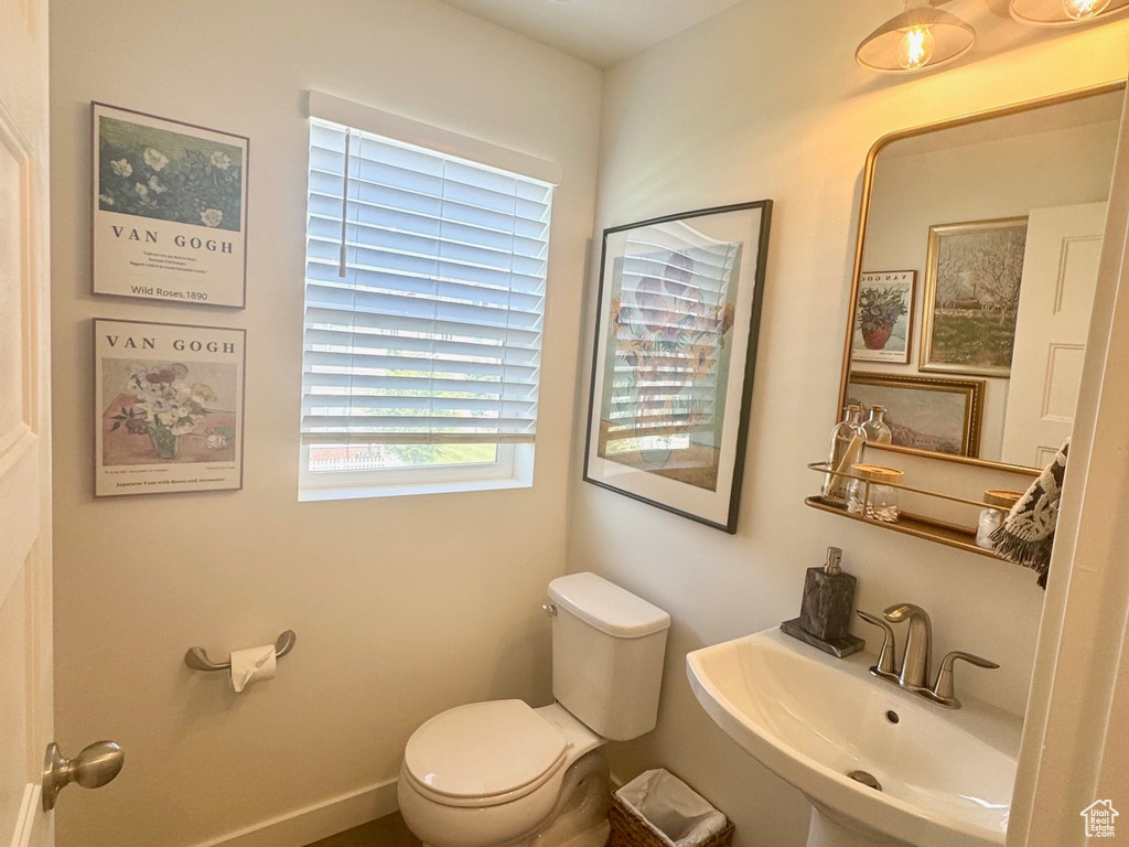 Bathroom with wood finished floors, toilet, and baseboards