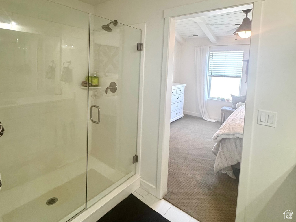 Ensuite bathroom with a shower stall, baseboards, and tile patterned floors
