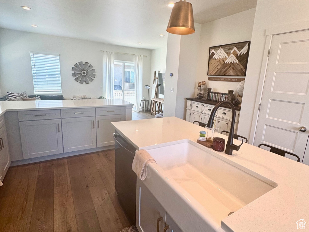 Kitchen with dishwasher, dark wood-style floors, decorative light fixtures, a sink, and recessed lighting
