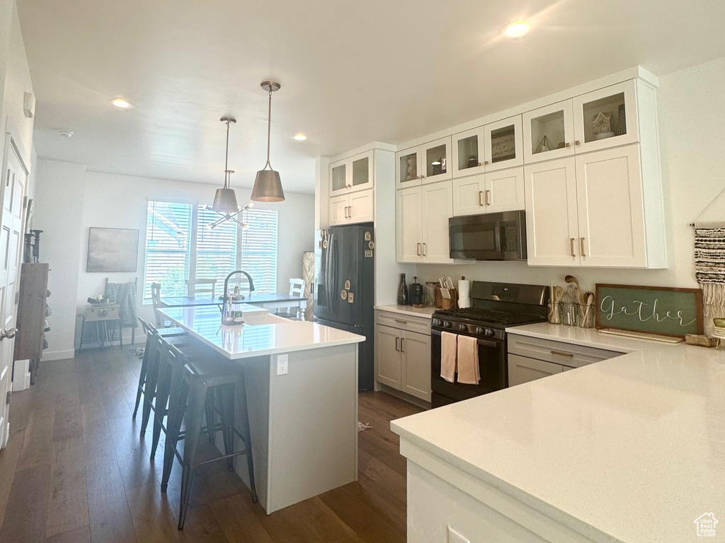 Kitchen featuring black appliances, recessed lighting, dark wood finished floors, an island with sink, and white cabinets