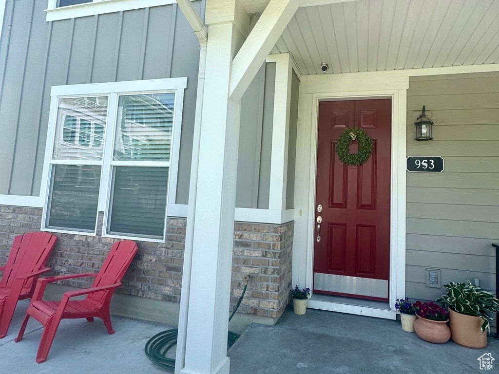 Doorway to property with board and batten siding, covered porch, and stone siding
