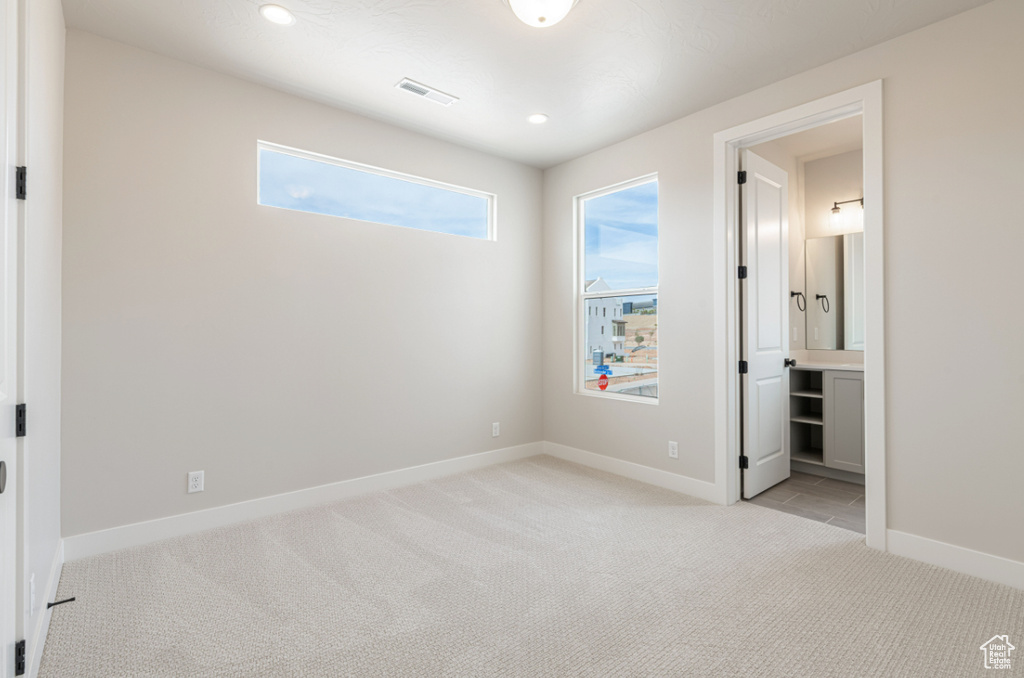 Unfurnished bedroom featuring light carpet, baseboards, recessed lighting, and ensuite bathroom