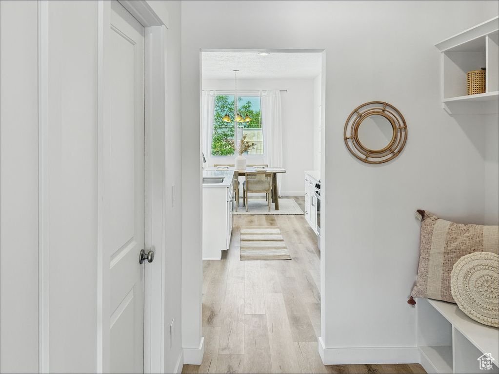 Corridor featuring light wood-style floors, a sink, and baseboards