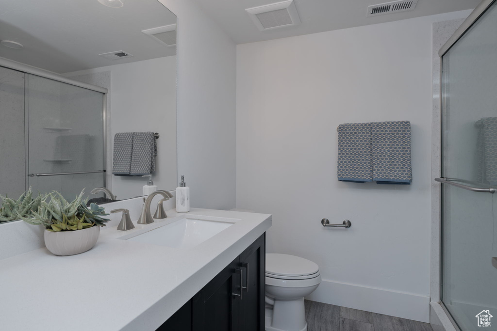 Full bathroom featuring vanity, a stall shower, toilet, wood finished floors, and baseboards
